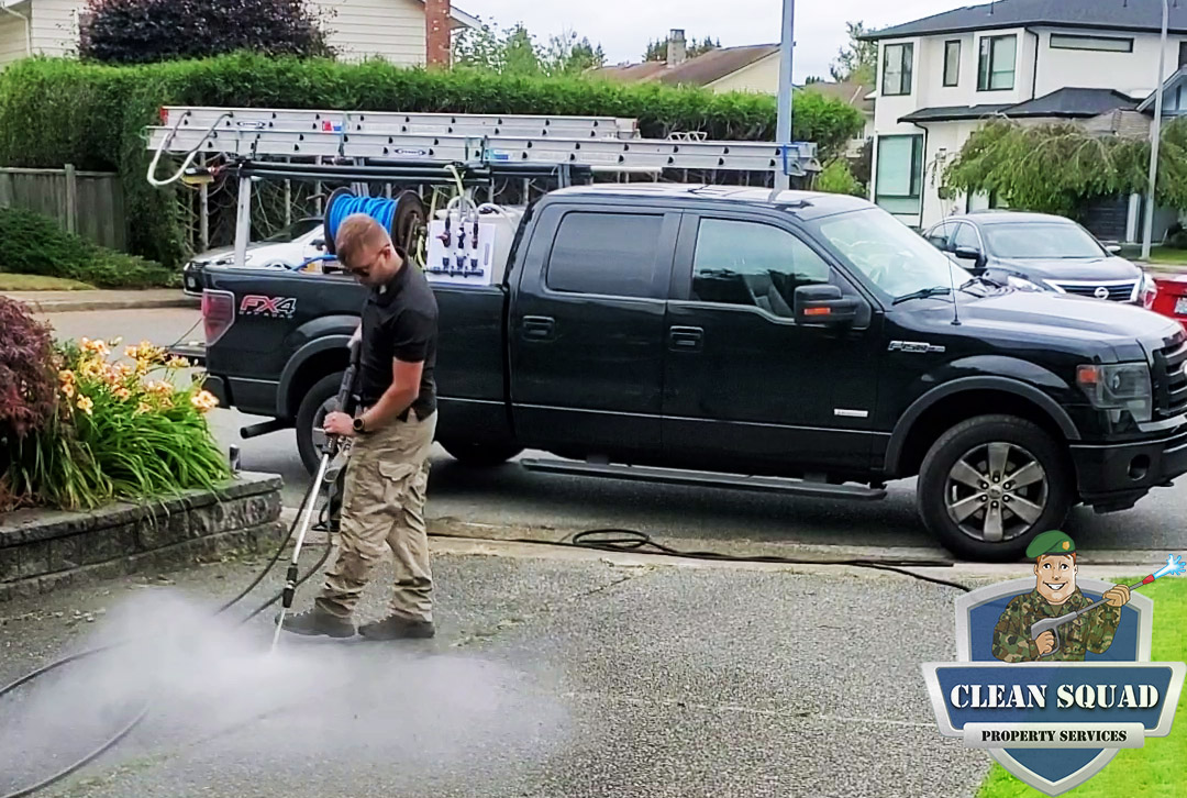 a clean squad employee pressure washing a concrete driveway