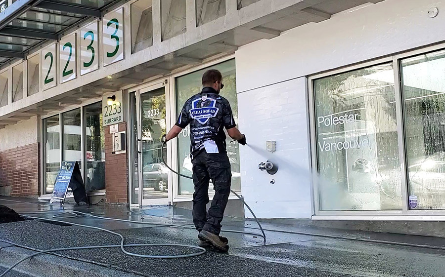 a clean squad employee soft washing the side of the polestar vancouver car dealership building