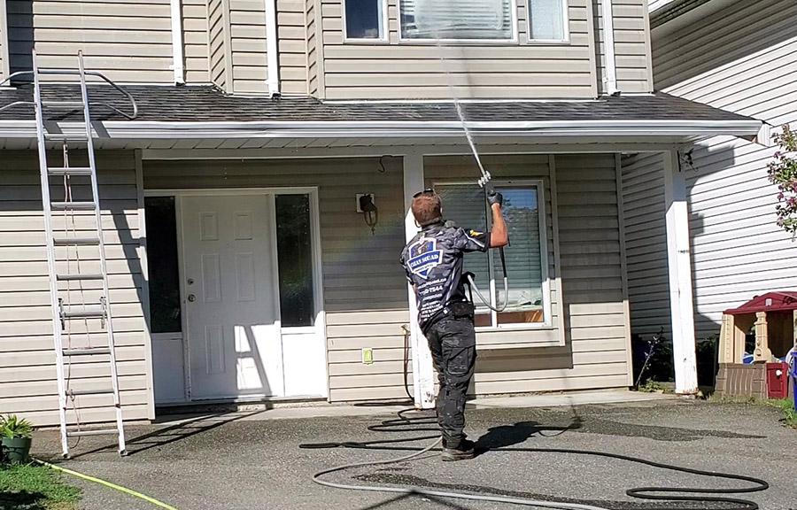 A clean squad employee soft washing soffits on a home in mosqueum vancouver
