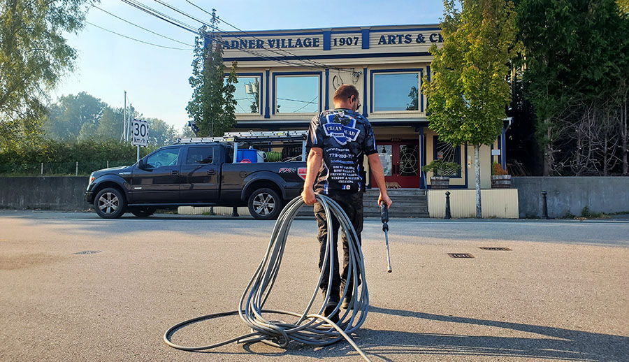 a team member seting up to pressure wash in front of the ladner village building