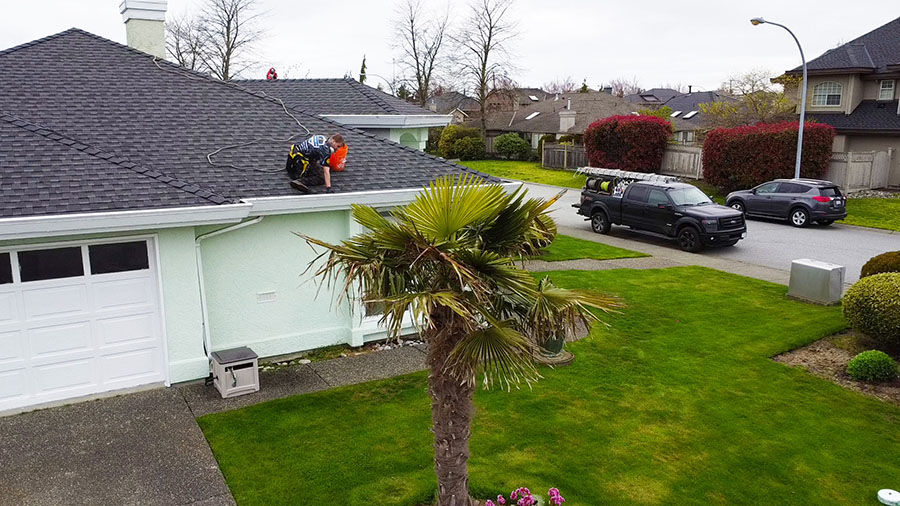 a team member cleaning gutters on a home in point grey vancouver