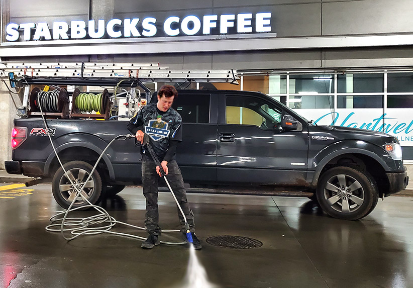 a team member power washing outside of a starbucks store
