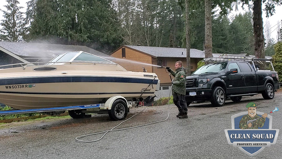 a clean squad employee pressure washing a boat