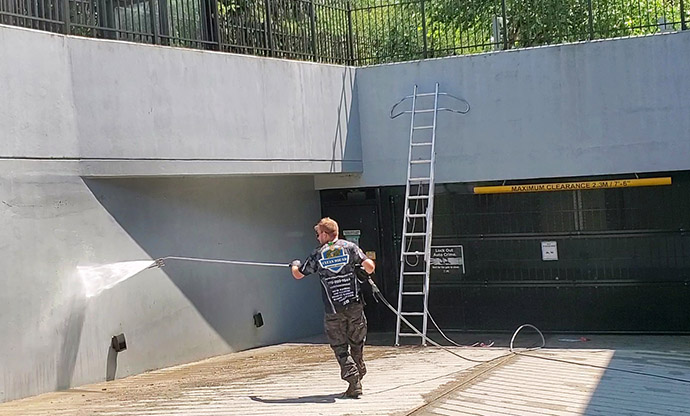 a clean squad employee pressure washing concrete wall to underground parking entrance in vancouver