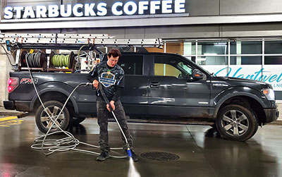 a team member pressure washing in front of a starbucks