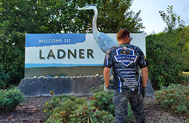 a team member standing in front of the ladner highway sign