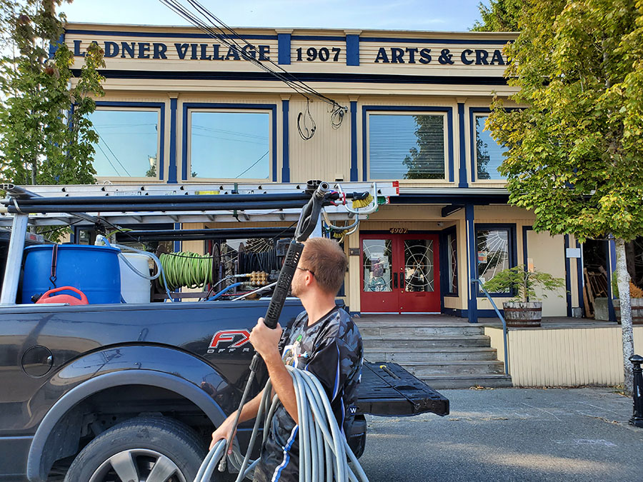 a team member unloading equipment from the work truck in front of the ladner village building