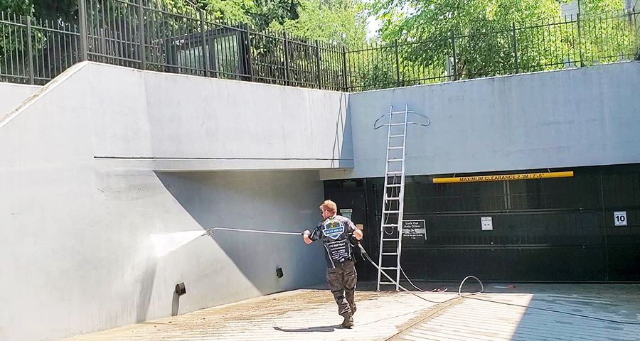 clean squad team member pressure washing parkade entrance