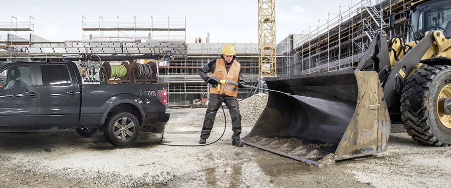 a team member pressure washing large machine on construction site